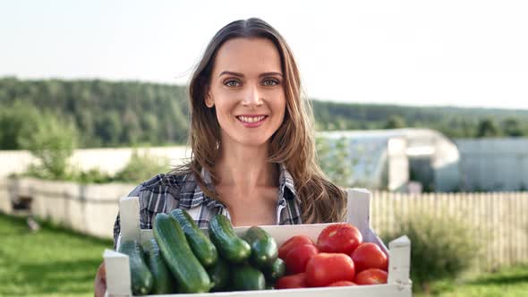 Female Farmer Posing with Box of Fresh Cucumber and Tomatoes