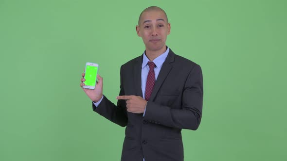 Happy Bald Multi Ethnic Businessman Showing Phone and Giving Thumbs Up