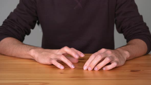 Bored Man Sitting And Tapping Fingers On Wooden Table. close up