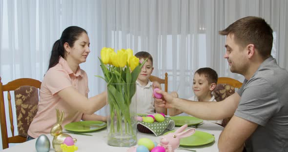 Family Sit at the Holiday Table Clash Colorful Eggs