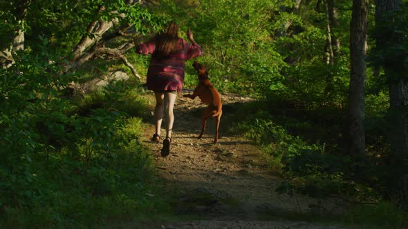Woman running with her dog on a forest path