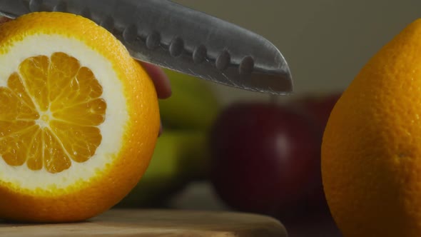 Closeup of Hand with Kitchen Knife Slicing Orange Indoors