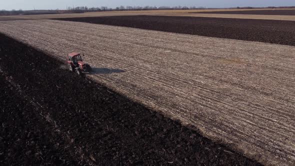 a tractor with a red cab plows the field