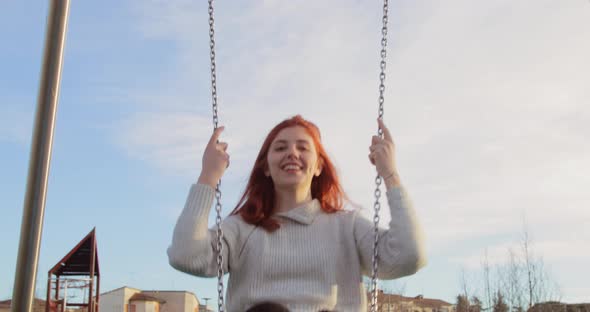 Young Beautiful Girl Has Fun in a Park with the Swing in the Nature