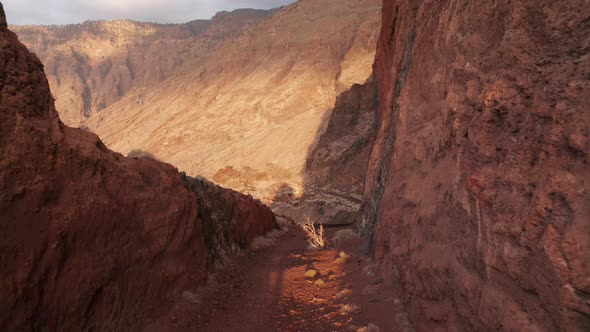 Aerial dolly over abandoned road cut between the red rocks to caldera