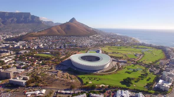 Aerial travel drone view of Cape Town, South Africa with Table Mountain and stadium.