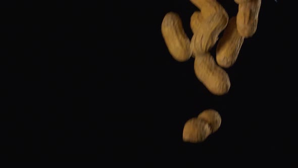 Peanuts in shells falling in slow motion against a black background