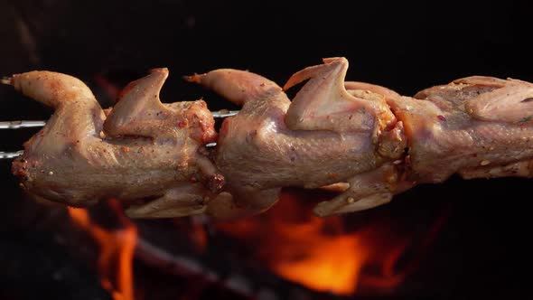 Closeup of the Raw Marinated Quails on Long Skewers Roasting Above an Open Fire