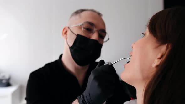 A Professional Dentist in a Protective Mask Works with a Patient in the Clinic