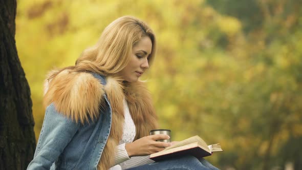 Female Drinking Warming Beverage From Thermos Cup While Reading Book, Solitude