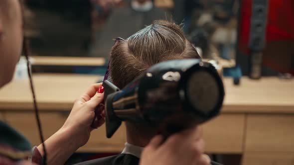 Barbershop: a woman barber cuts a client's man's hair