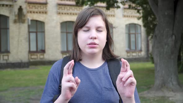 Plump Caucasian Boy with Closed Eyes Showing Hope Gesture and Talking. Close-up Portrait of Hopeful