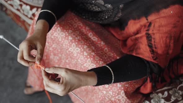 Woman siting on bed and knitting with red wool. Directly above footage of knit work tie-up hand work