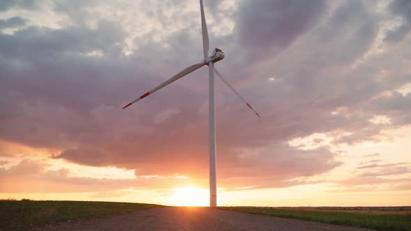 Time lapse windmill is spinning against the backdrop of a beautiful cloudy sky and sunset.