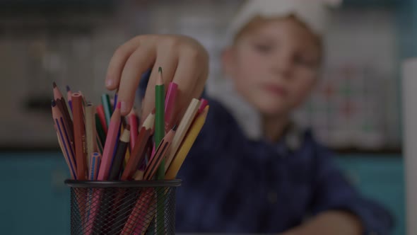 Kid Drawing Pirate's Ship with Color Pencils While Playing Pirate's Game with Skull and Crossbones