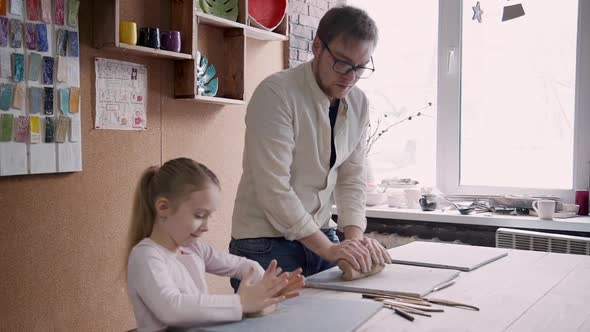 Man Helping Little Girl Making Pottery in Workshop Studio