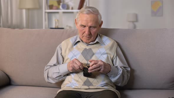 Sad Senior Man Sitting on Sofa and Showing Empty Wallet at Camera, Poverty