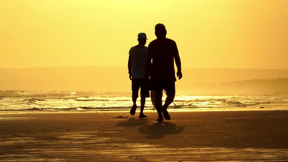 Fisherman collecting shellfish during sunset; golden light, two black silhouettes passing by