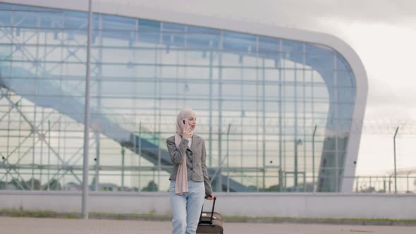 Pretty Traveler Tourist Arabian Woman in Hijab Carrying Suitcase and Talking Phone