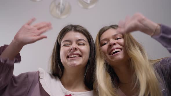 Two Carefree Young Women Leaning to Camera Waving Smiling