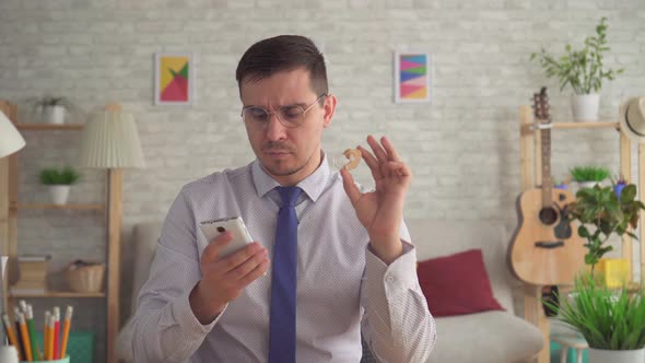 Man with a Hearing Aid in His Hand Looking for Information on the Internet on a Smartphone