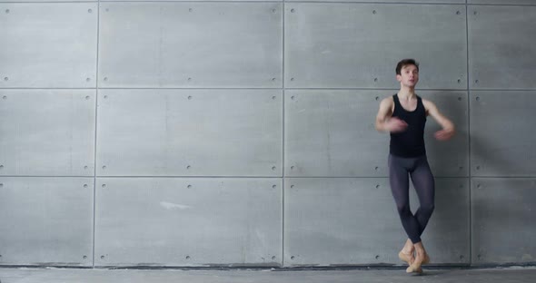 Male Ballet Dancer Performs Acrobatic Elements of a Ballet Dance on a Gray Background  Slow Motion