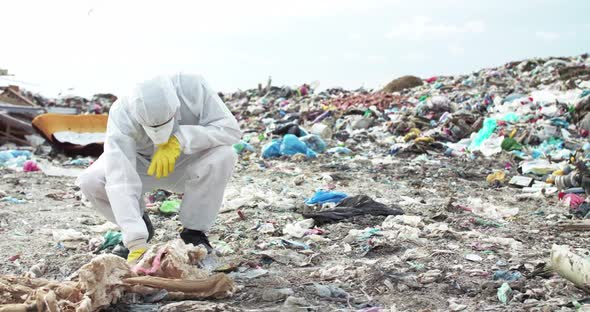 Virologist in Protective Costume and Gas Mask Coming and Examining Landfill