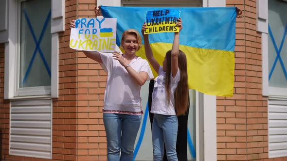 Ukrainian Mother and Daughters Posing with Help Ukraine Placards Standing on Summer Porch Outdoors
