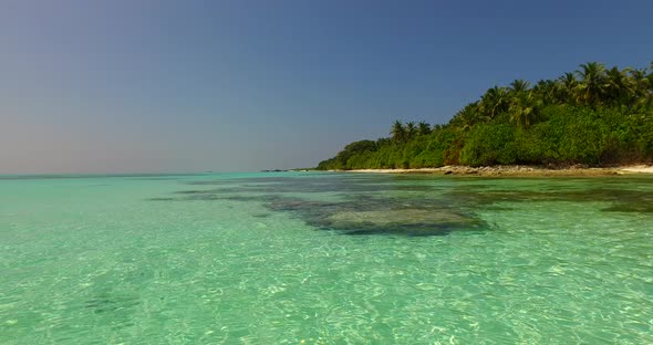 Beautiful above island view of a white paradise beach and aqua blue ocean background in vibrant 4K