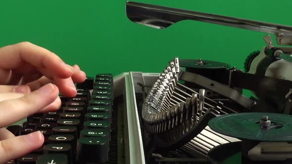 The girl is typing on a retro typewriter on a green background. Chromakey.