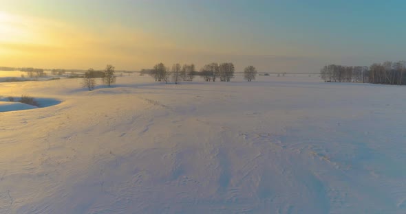 Aerial View of Cold Arctic Field Landscape Trees with Frost Snow Ice River and Sun Rays Over Horizon