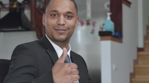 Positive Young African American Man Showing Thumb Up Looking at Camera Sitting in Home Office