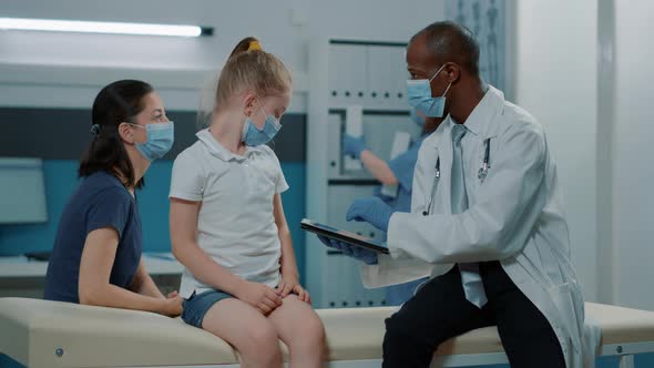 Pediatrician Using Tablet to Take Notes at Consultation Appointment