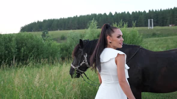 Brunette Model with Ponytail Walks to Black Horse on Lawn