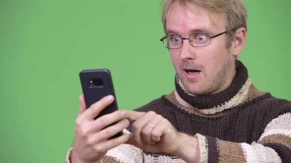 Studio Shot of Happy Handsome Man Using Phone and Looking Surprised