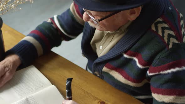 Elderly Man with Smoking Pipe Enjoying Book