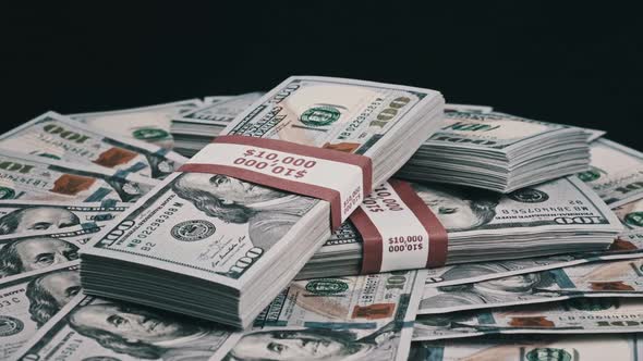 Bundles of Dollars Lying on a Pile of Money and Rotate on Black Background