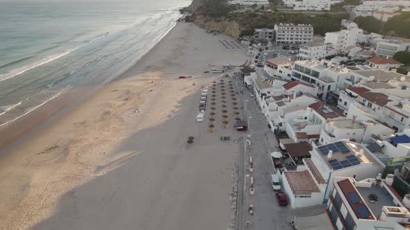 Setting sun draws long shadows into the sand of Salema beach in the portuguese region of Algarve