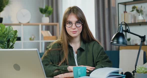 Young Woman in Glasses which Sitting in front of Camera in Cozy Home Office