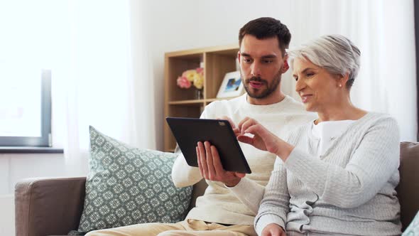 Old Mother and Adult Son with Tablet Pc at Home