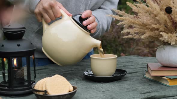 Female Hands Pouring Tea in Mug Drinking Tea in Autumn Outdoors