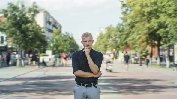 Tiltdown Time Lapse of Attractive Young Businessman Standing Outdoors in Busy Street with Pensive