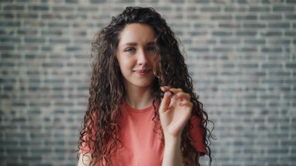 Portrait of Cute Woman Winding Hair Around Finger Flirting Looking at Camera