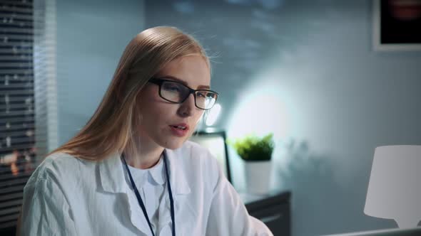 Close-up of Female Psychologist in Eyeglasses and Lab Coat Making Video Call with Patient
