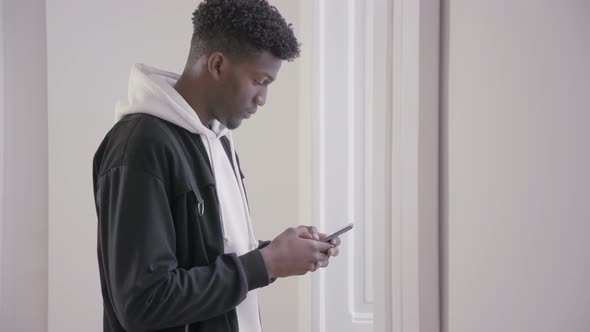 Young Guy Using Smartphone, Looking at Camera and Smiling