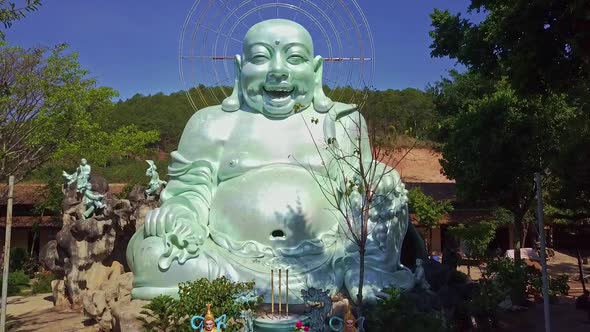 Drone Moves Close To Laughing Buddha Against Hills