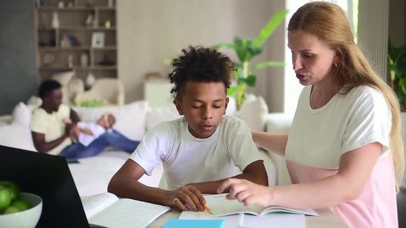 Woman and Boy Doing Homework While Sitting at Table with Computer in Apartment Room Spbd