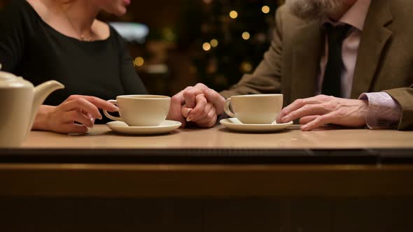 Hands of two people and cups of tea at the bar. Close-up of the hands of two