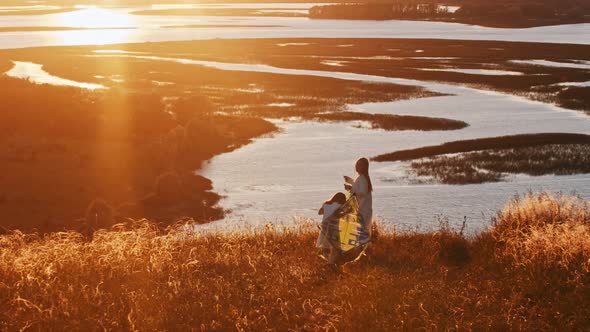 Young Woman with Her Daughter Playing with the Kite on the Hill at Sunset