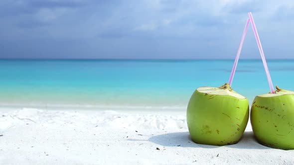 Fresh Green Coconuts Juice on Sandy Beach with Turquoise Sea Background